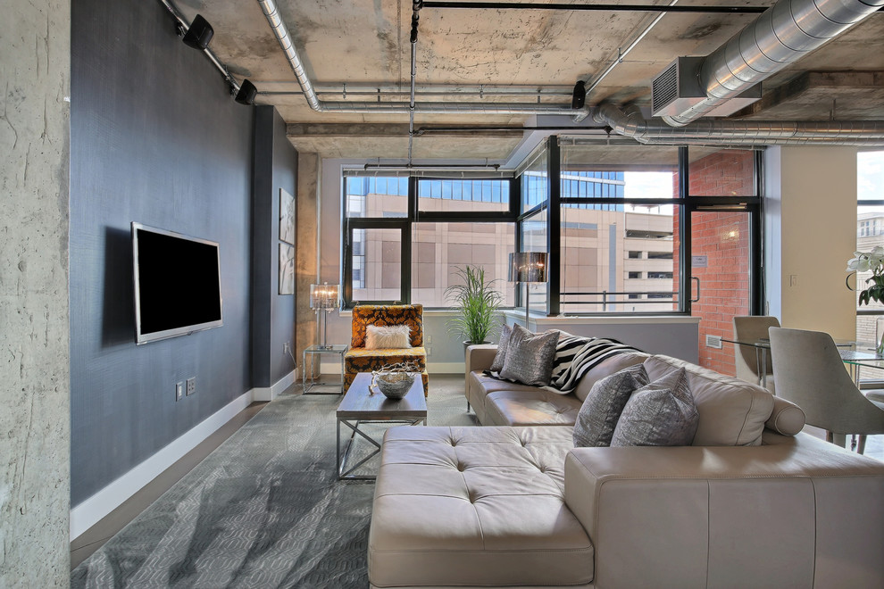 Idee per un piccolo soggiorno industriale aperto con pareti blu, pavimento in cemento, nessun camino e TV a parete