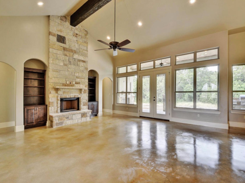 Example of a large tuscan formal and open concept concrete floor living room design in Austin with beige walls, a standard fireplace and a stone fireplace
