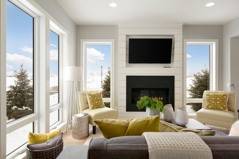 Photo of a classic open plan living room in Minneapolis with grey walls, light hardwood flooring, a standard fireplace, a timber clad chimney breast and a wall mounted tv.