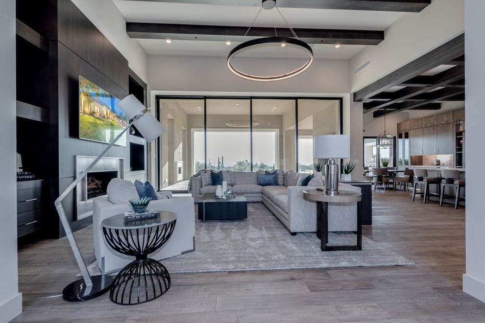 Expansive modern formal open plan living room in Phoenix with grey walls, light hardwood flooring, a standard fireplace, a metal fireplace surround, a built-in media unit and grey floors.