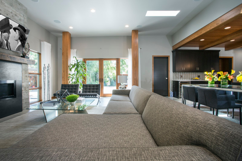 Offenes Klassisches Wohnzimmer mit grauer Wandfarbe, Betonboden, Kaminumrandung aus Stein und TV-Wand in Salt Lake City