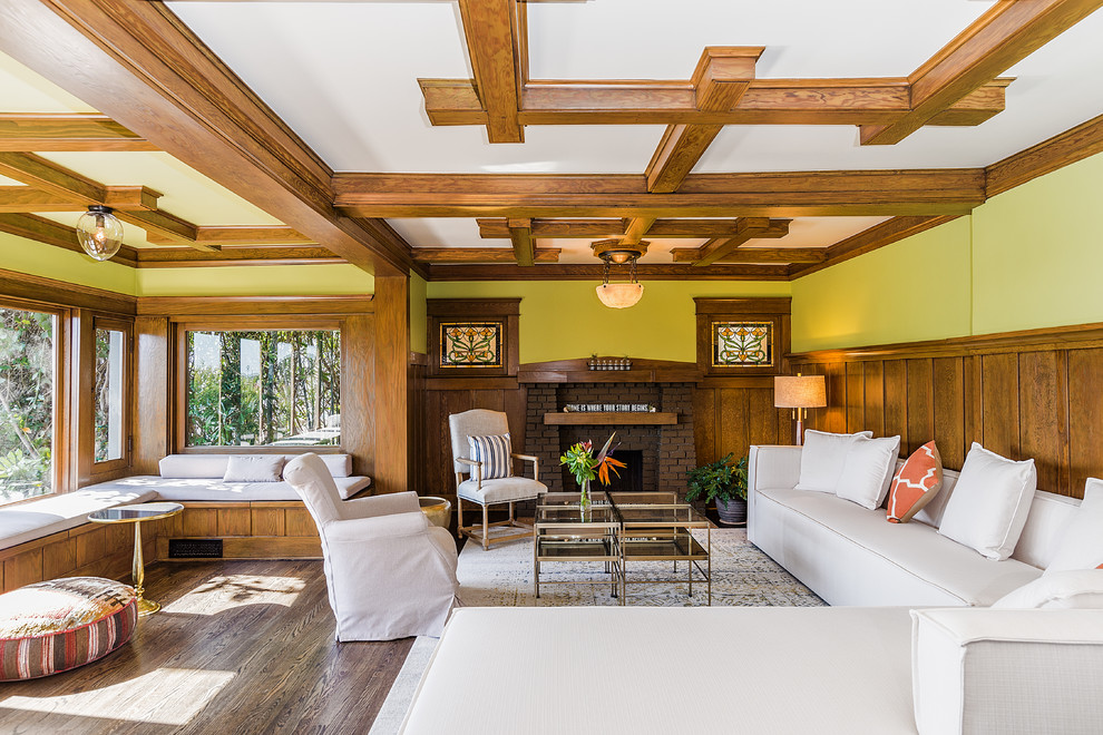 Inspiration for a traditional living room in Los Angeles with green walls, dark hardwood flooring, a standard fireplace, a brick fireplace surround and brown floors.