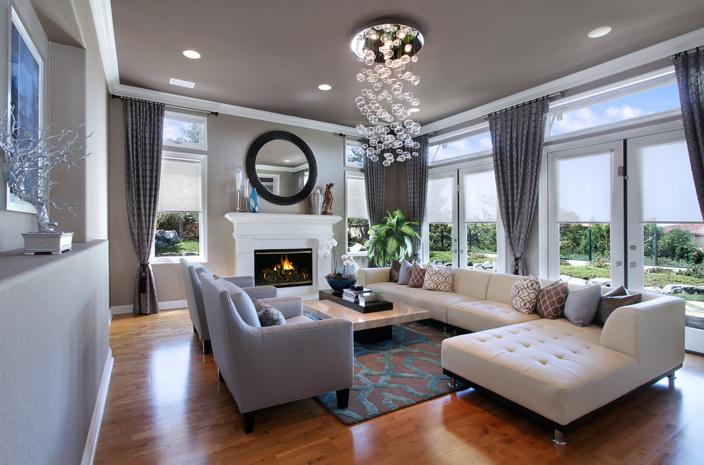 This is an example of a medium sized contemporary formal and grey and teal open plan living room in Orange County with grey walls, medium hardwood flooring, a standard fireplace, a wooden fireplace surround, no tv and brown floors.
