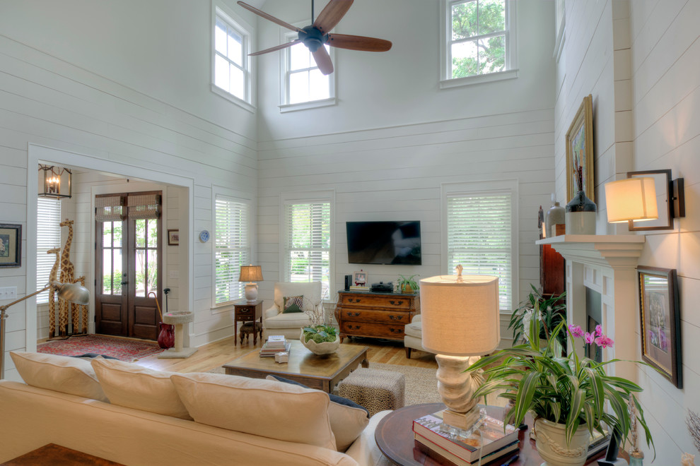 Foto på ett stort lantligt separat vardagsrum, med vita väggar, ljust trägolv, en väggmonterad TV och brunt golv