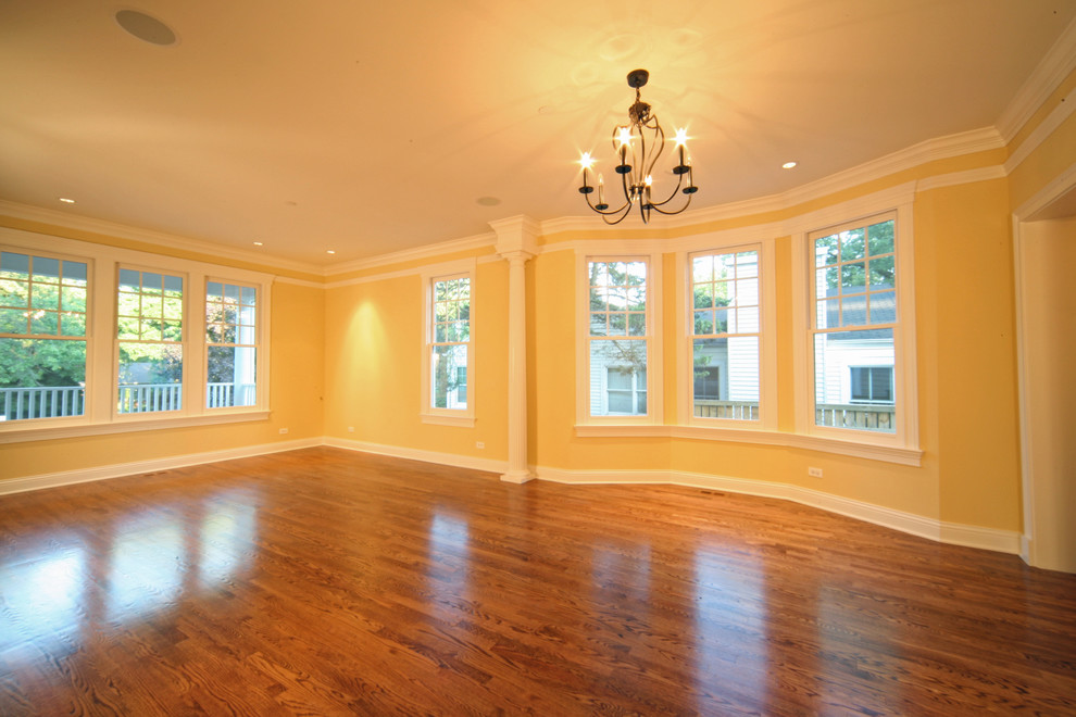 Ejemplo de salón abierto clásico grande con paredes amarillas y suelo de madera en tonos medios