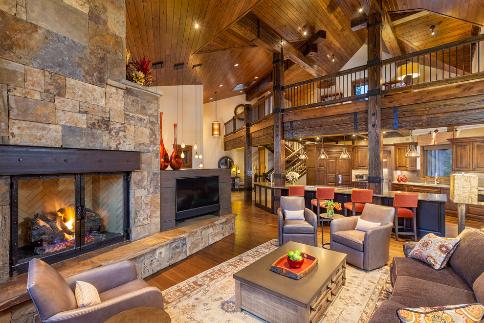 Design ideas for a rustic open plan living room in Denver with white walls, medium hardwood flooring, a standard fireplace and a stone fireplace surround.