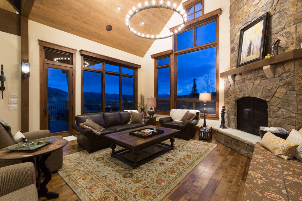 This is an example of a large rustic formal open plan living room in Denver with beige walls, dark hardwood flooring, a corner fireplace, a stone fireplace surround, no tv and brown floors.