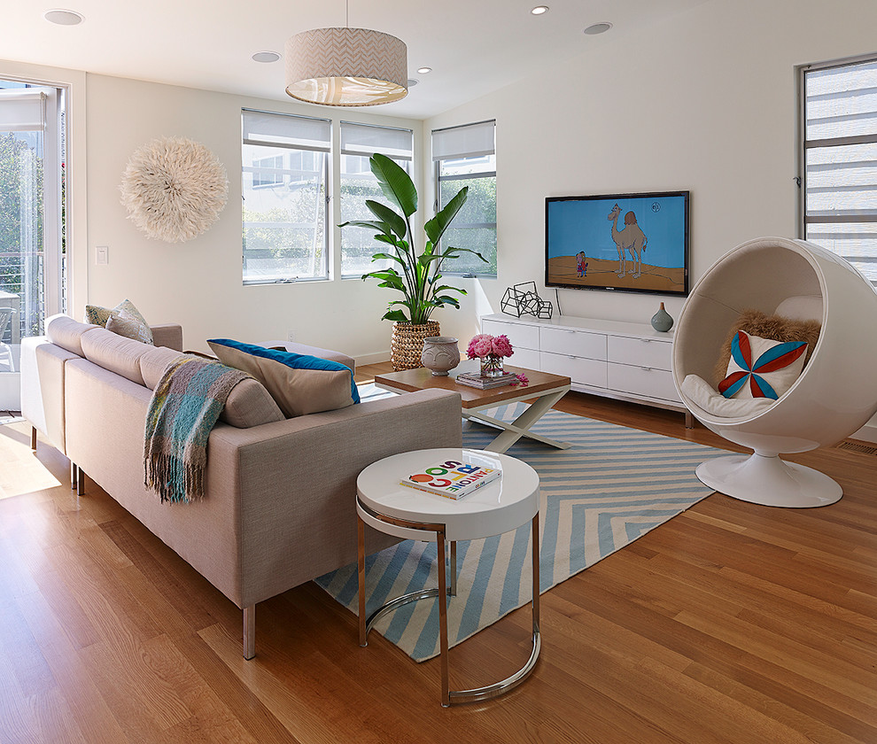 Cette image montre un salon design avec un mur blanc, un sol en bois brun et un téléviseur fixé au mur.