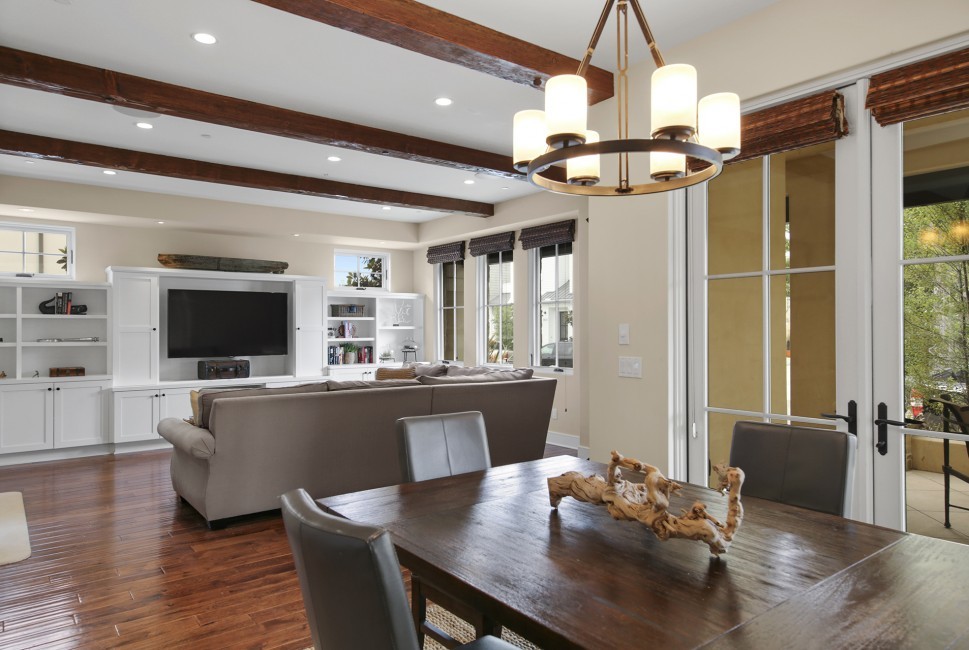 Offenes Klassisches Wohnzimmer mit beiger Wandfarbe, braunem Holzboden und freistehendem TV in Orange County