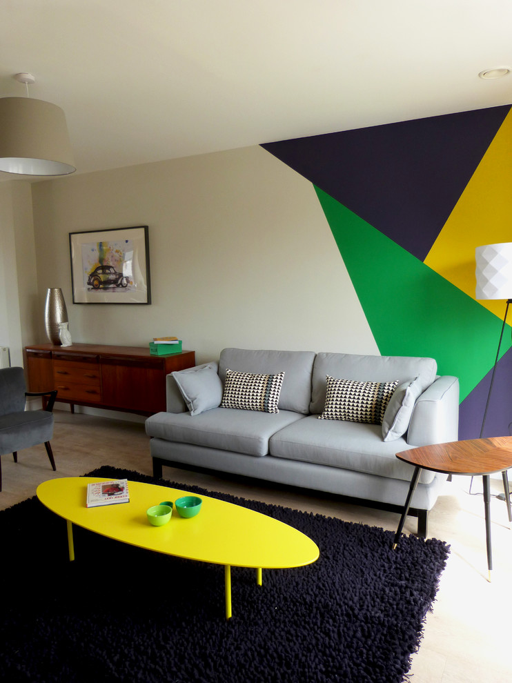 This is an example of a medium sized eclectic open plan living room in Dublin with multi-coloured walls, light hardwood flooring and a freestanding tv.