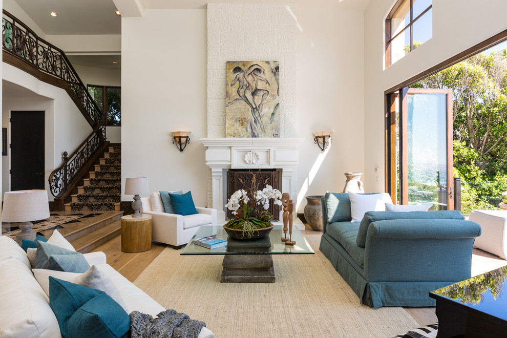 This is an example of a mediterranean open plan living room in Los Angeles with white walls, light hardwood flooring and a standard fireplace.