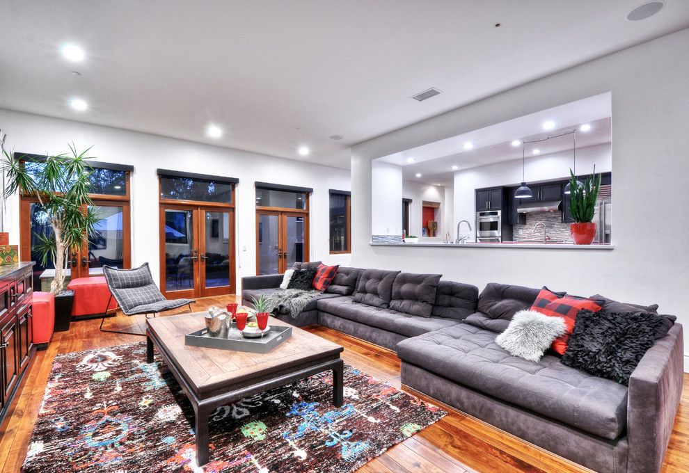 Modelo de salón para visitas abierto clásico renovado de tamaño medio con paredes grises, suelo de madera en tonos medios y televisor colgado en la pared
