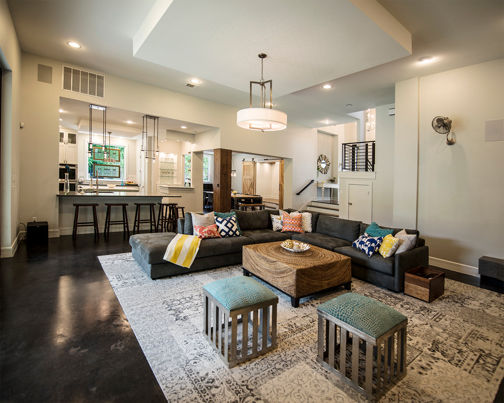 This is an example of a traditional open plan living room in Austin with concrete flooring and white walls.