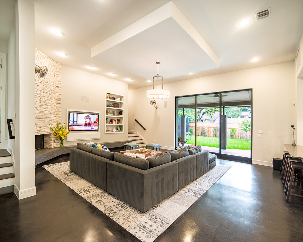 Offenes Klassisches Wohnzimmer mit weißer Wandfarbe, Betonboden, Eckkamin, Kaminumrandung aus Stein und TV-Wand in Austin