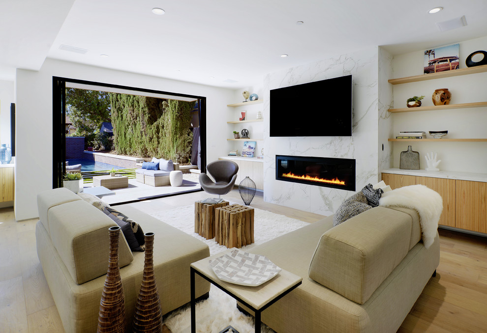 Modernes Wohnzimmer mit weißer Wandfarbe, hellem Holzboden, Gaskamin, Kaminumrandung aus Stein, TV-Wand und beigem Boden in Los Angeles