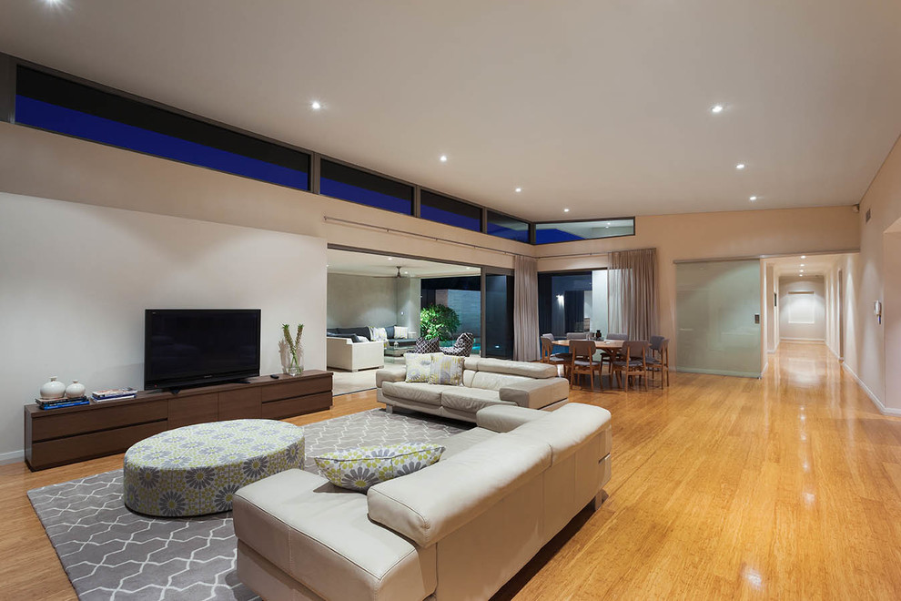Inspiration for a large modern formal open plan living room in Perth with beige walls, medium hardwood flooring, no fireplace and a freestanding tv.
