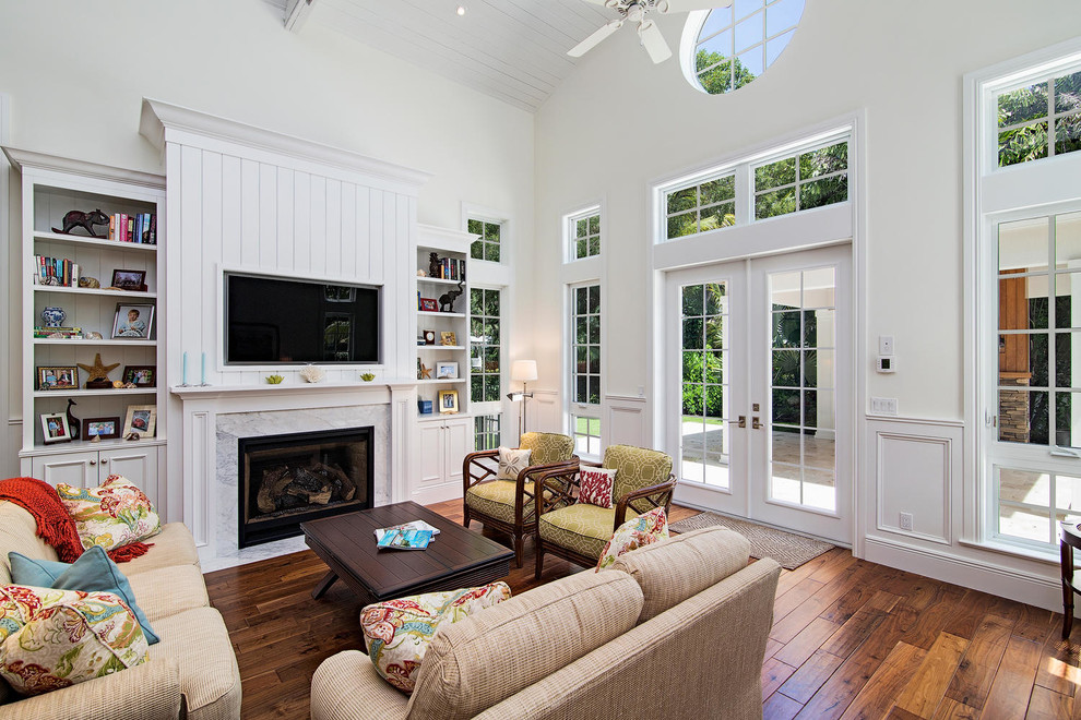 Mittelgroßes, Offenes Klassisches Wohnzimmer mit weißer Wandfarbe, braunem Holzboden, Kamin, Kaminumrandung aus Stein und Multimediawand in Miami