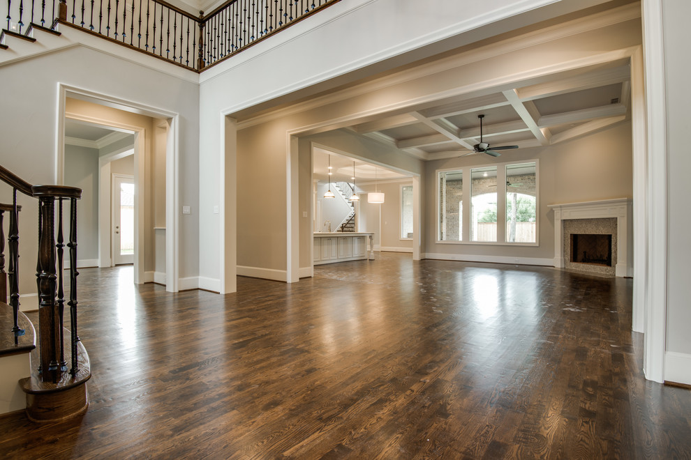 Klassisches Wohnzimmer mit grauer Wandfarbe, braunem Holzboden, Eckkamin und Kaminumrandung aus Holz in Dallas