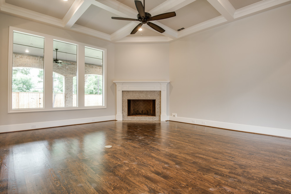 Offenes Klassisches Wohnzimmer mit grauer Wandfarbe, braunem Holzboden, Eckkamin und Kaminumrandung aus Holz in Dallas