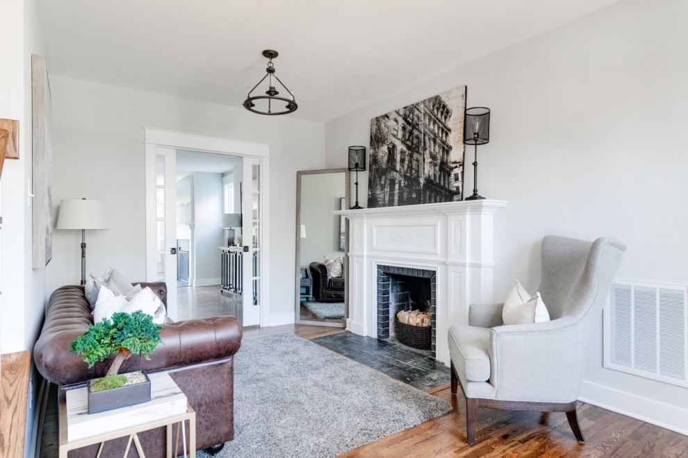 Inspiration for a mid-sized timeless enclosed medium tone wood floor and brown floor living room remodel in Richmond with gray walls, a standard fireplace and a wood fireplace surround