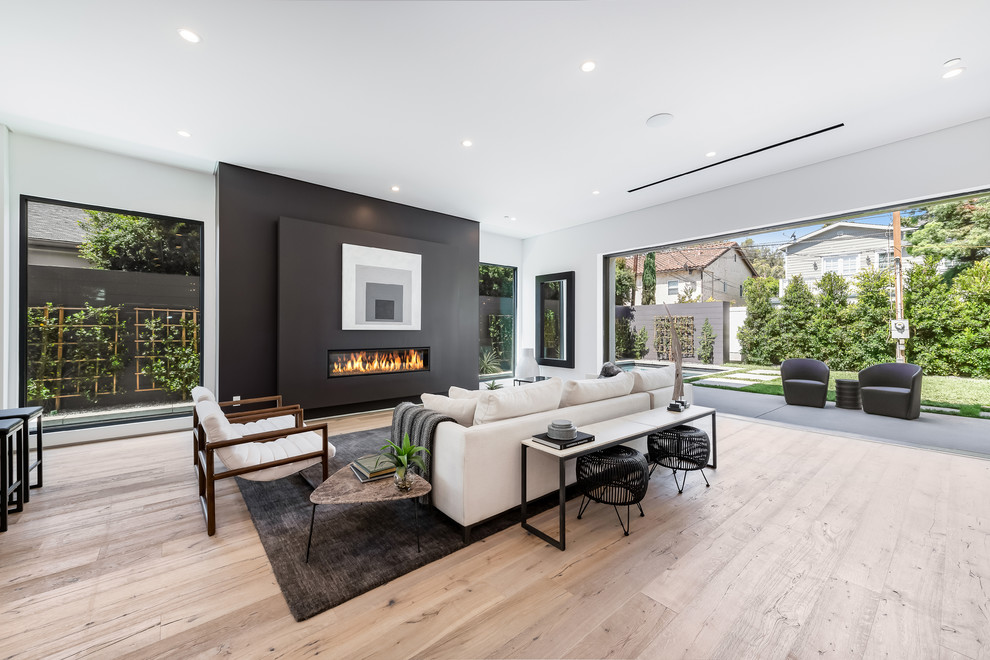Repräsentatives Modernes Wohnzimmer mit schwarzer Wandfarbe, hellem Holzboden, Gaskamin und beigem Boden in Los Angeles