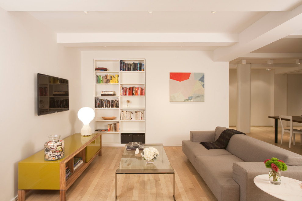Immagine di un soggiorno minimal di medie dimensioni con libreria e TV a parete