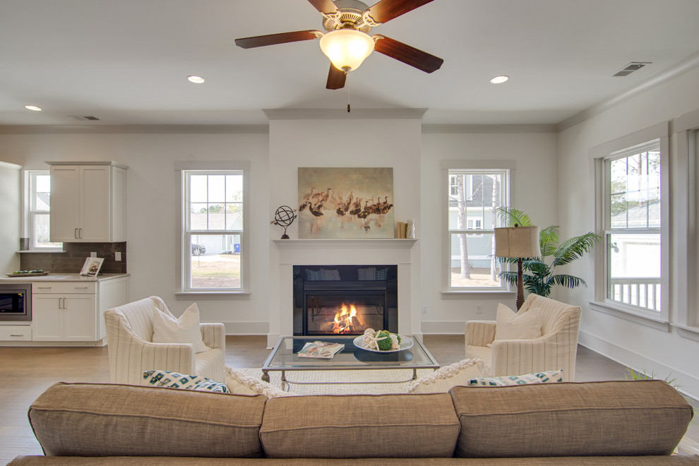 This is an example of a traditional formal open plan living room in Charleston with medium hardwood flooring, a standard fireplace, a stone fireplace surround, white walls, no tv and beige floors.