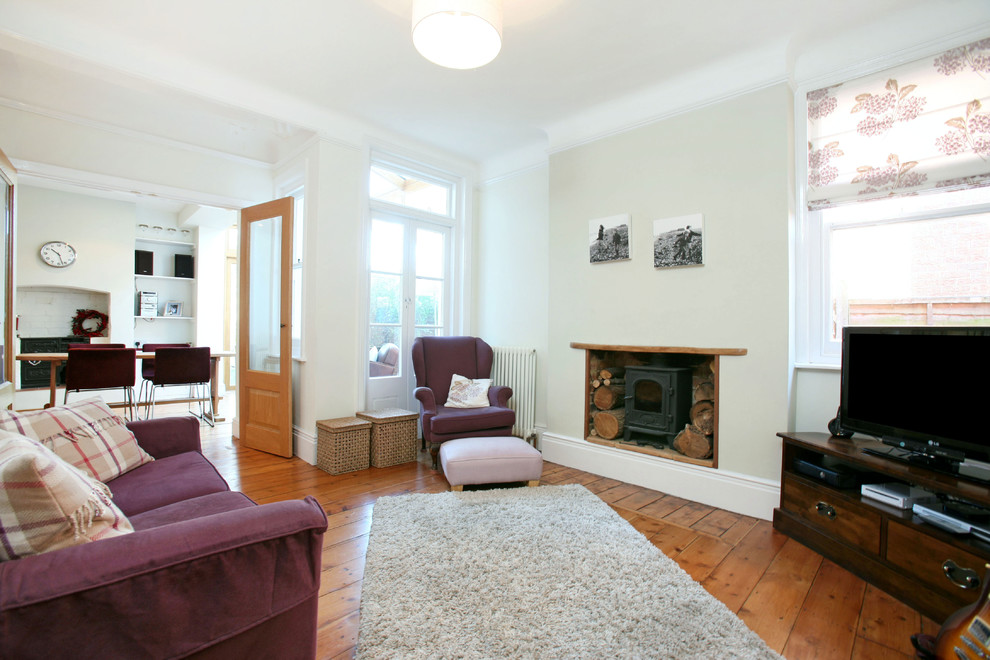 Cette photo montre un salon chic avec un mur beige, un sol en bois brun, une cheminée standard et un téléviseur indépendant.