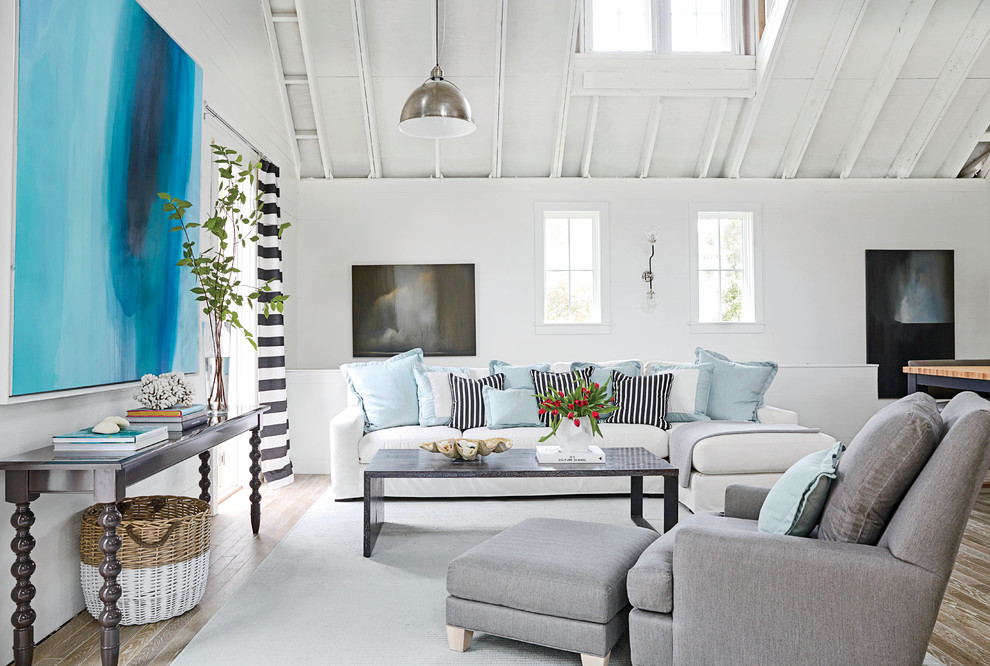 This is an example of a large coastal open plan living room in Miami with white walls, medium hardwood flooring and no tv.