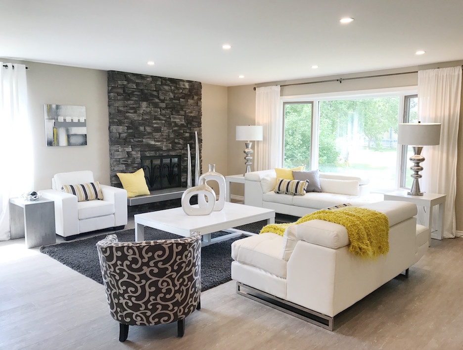 This is an example of a large modern formal open plan living room in Other with beige walls, laminate floors, a standard fireplace, a brick fireplace surround, a freestanding tv and grey floors.