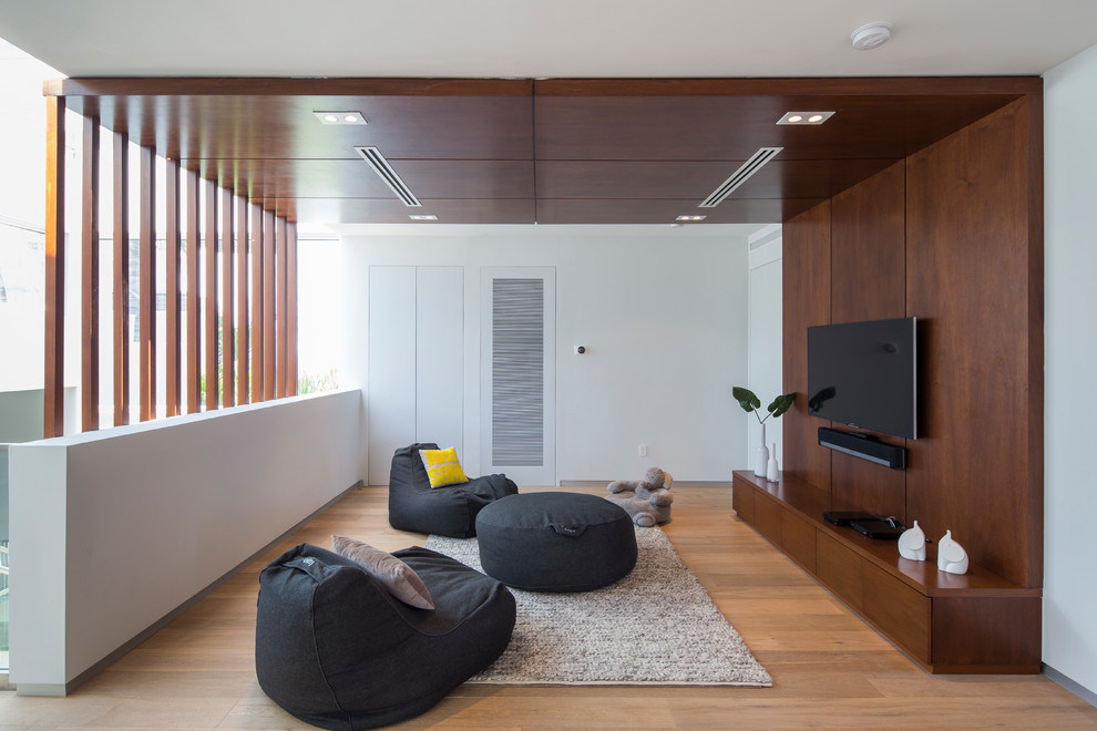 Example of a trendy medium tone wood floor and brown floor living room design in Miami with white walls and a wall-mounted tv