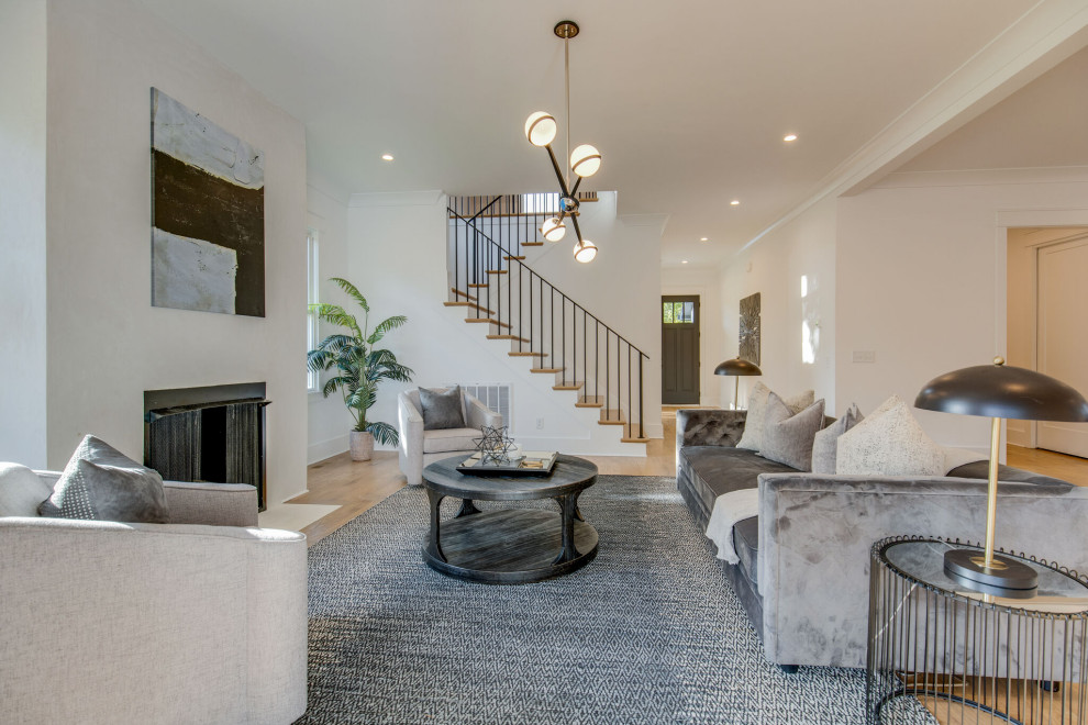 Immagine di un soggiorno chic aperto con pareti bianche, pavimento in legno massello medio, camino classico e pavimento marrone