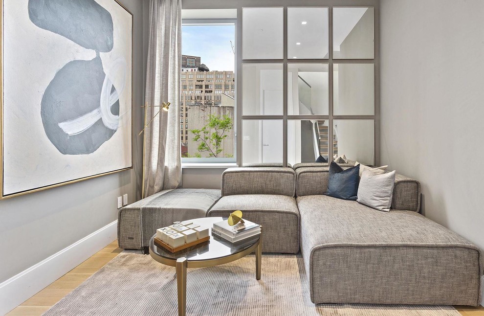 Foto di un soggiorno minimal con pareti grigie, parquet chiaro e pavimento beige