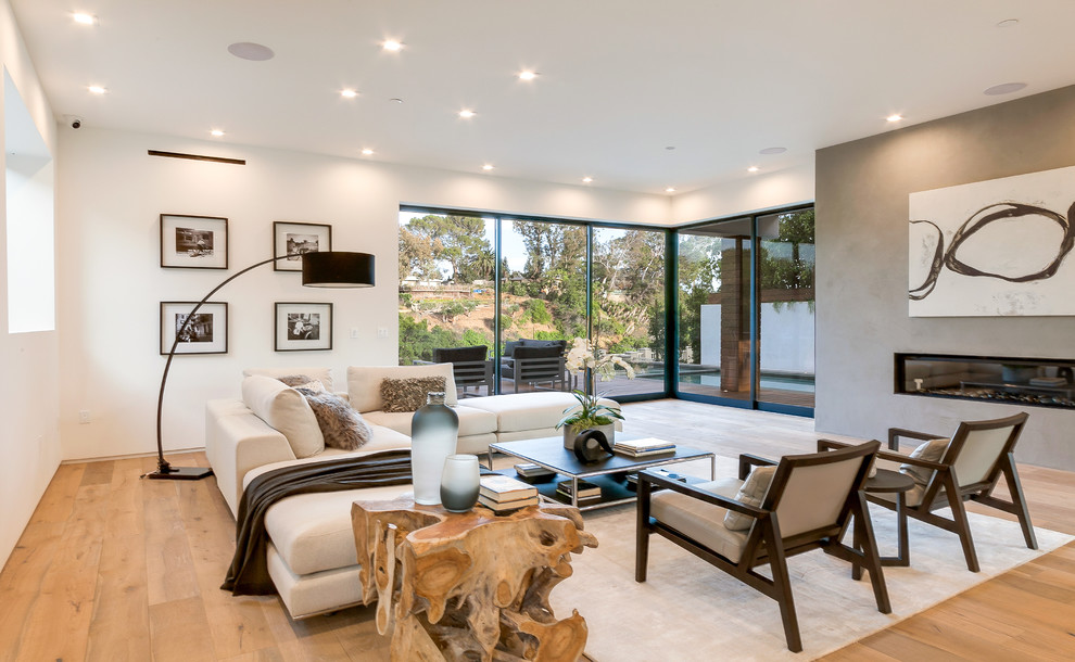 Repräsentatives, Offenes Modernes Wohnzimmer mit weißer Wandfarbe, hellem Holzboden, Gaskamin, Kaminumrandung aus Metall und beigem Boden in Los Angeles