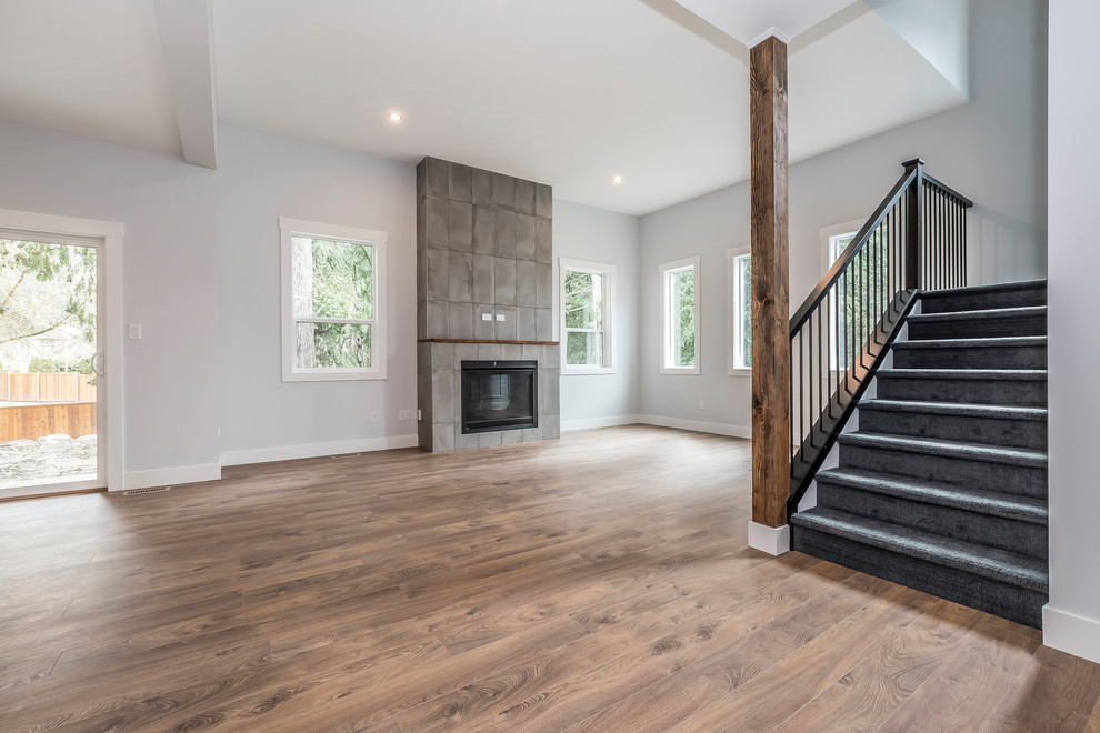 Large classic open plan living room in Vancouver with grey walls, laminate floors, a standard fireplace, a tiled fireplace surround and a wall mounted tv.