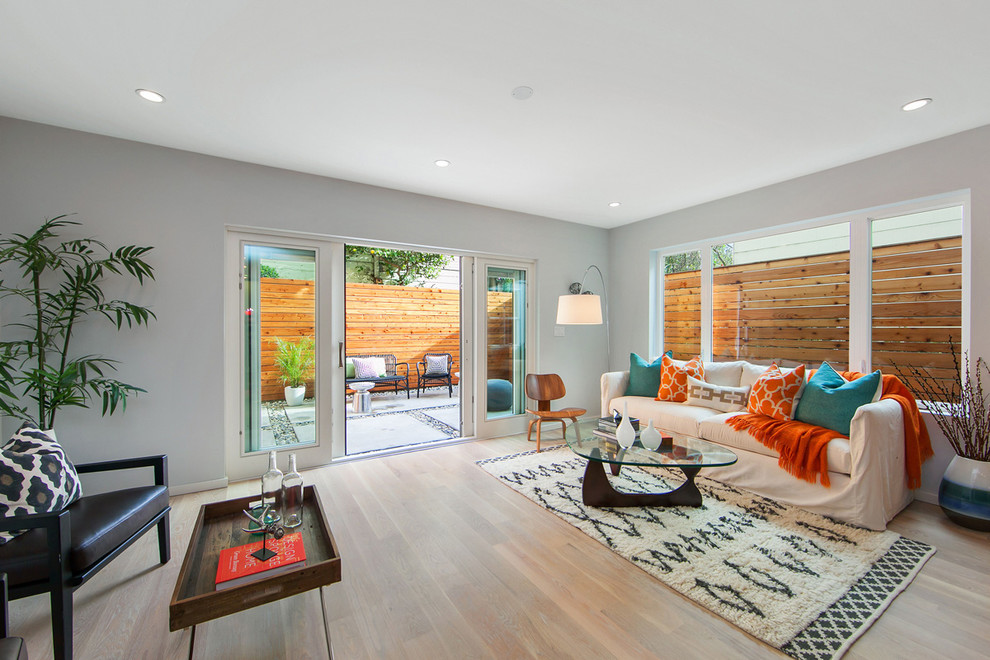 Foto de salón para visitas abierto contemporáneo de tamaño medio sin chimenea con paredes azules, suelo de madera en tonos medios y pared multimedia