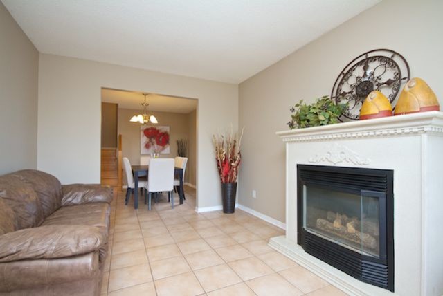 Example of a tuscan open concept ceramic tile living room design in Toronto with beige walls, a standard fireplace and a wood fireplace surround