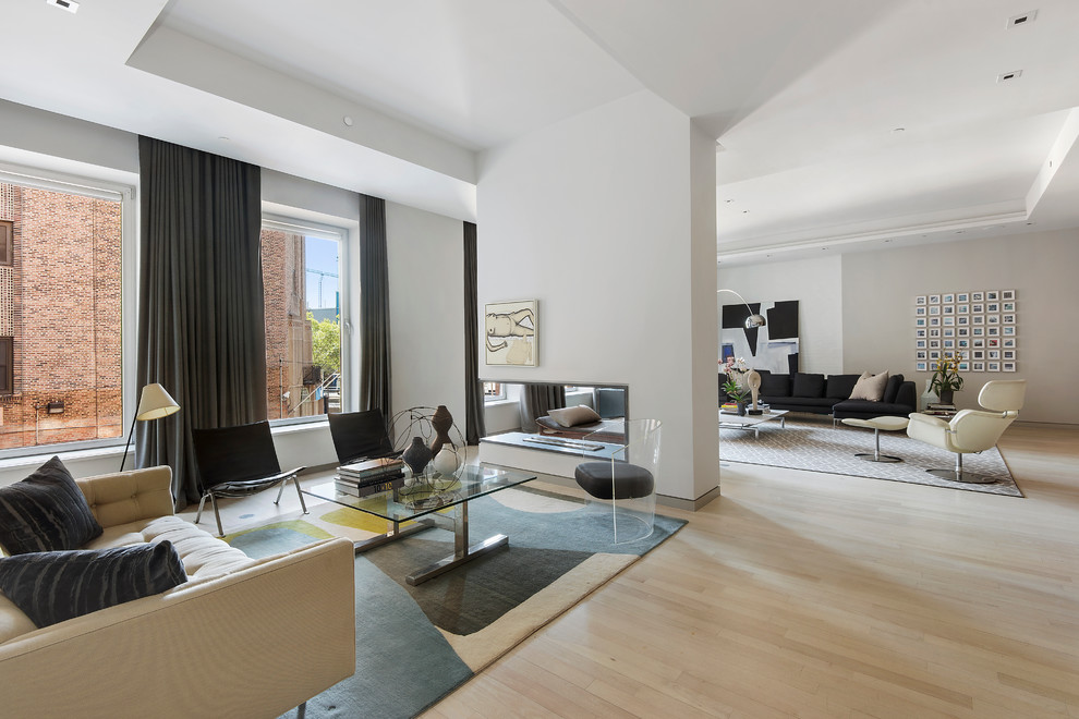 Immagine di un ampio soggiorno design aperto con sala formale, pareti bianche, parquet chiaro, camino bifacciale e nessuna TV