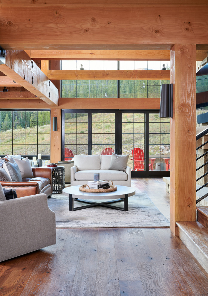 Example of a mountain style open concept medium tone wood floor and brown floor living room design in Denver