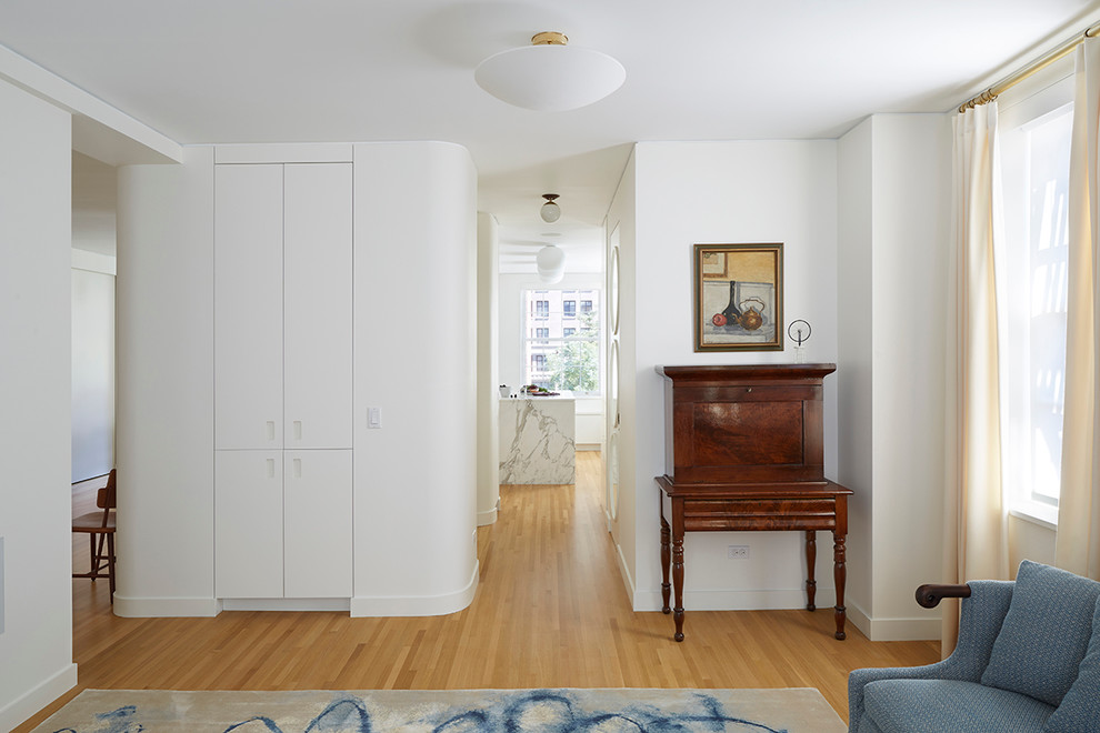 Mittelgroßes, Abgetrenntes Modernes Wohnzimmer ohne Kamin mit weißer Wandfarbe, hellem Holzboden und verstecktem TV in New York