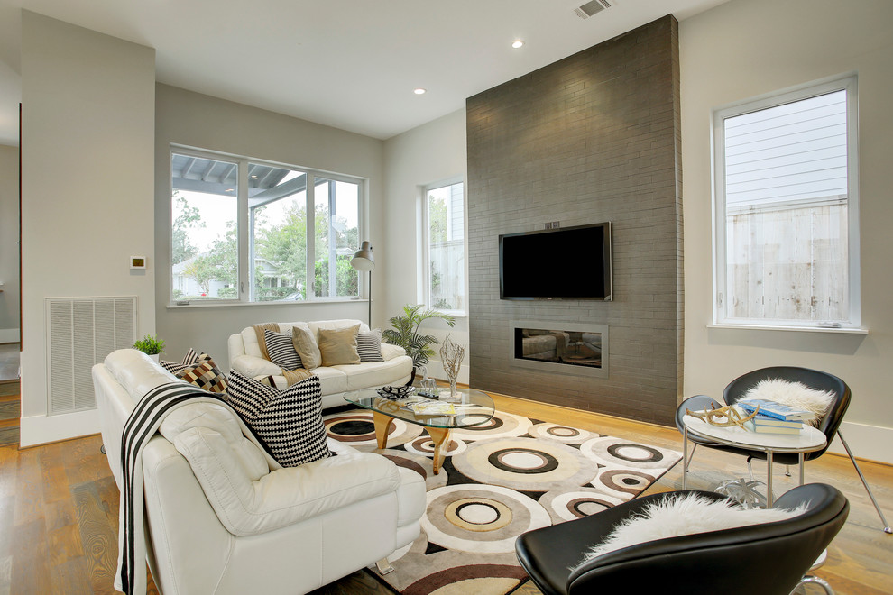 Esempio di un soggiorno minimal con pareti grigie, pavimento in legno massello medio, camino lineare Ribbon e TV a parete