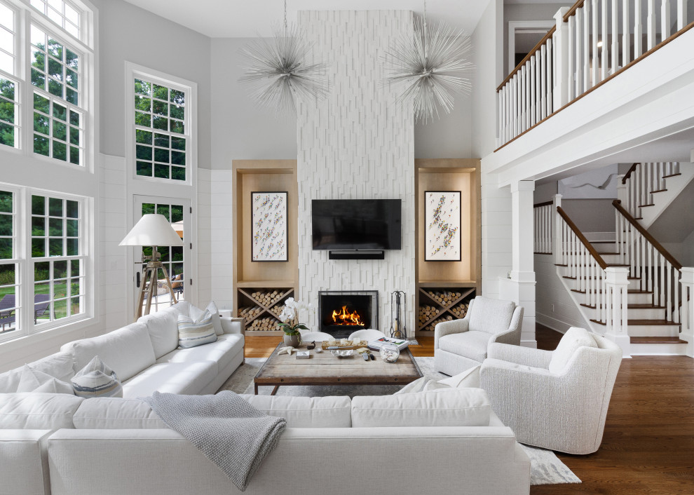 Large transitional formal and open concept medium tone wood floor and brown floor living room photo in New York with white walls, a standard fireplace and a wall-mounted tv