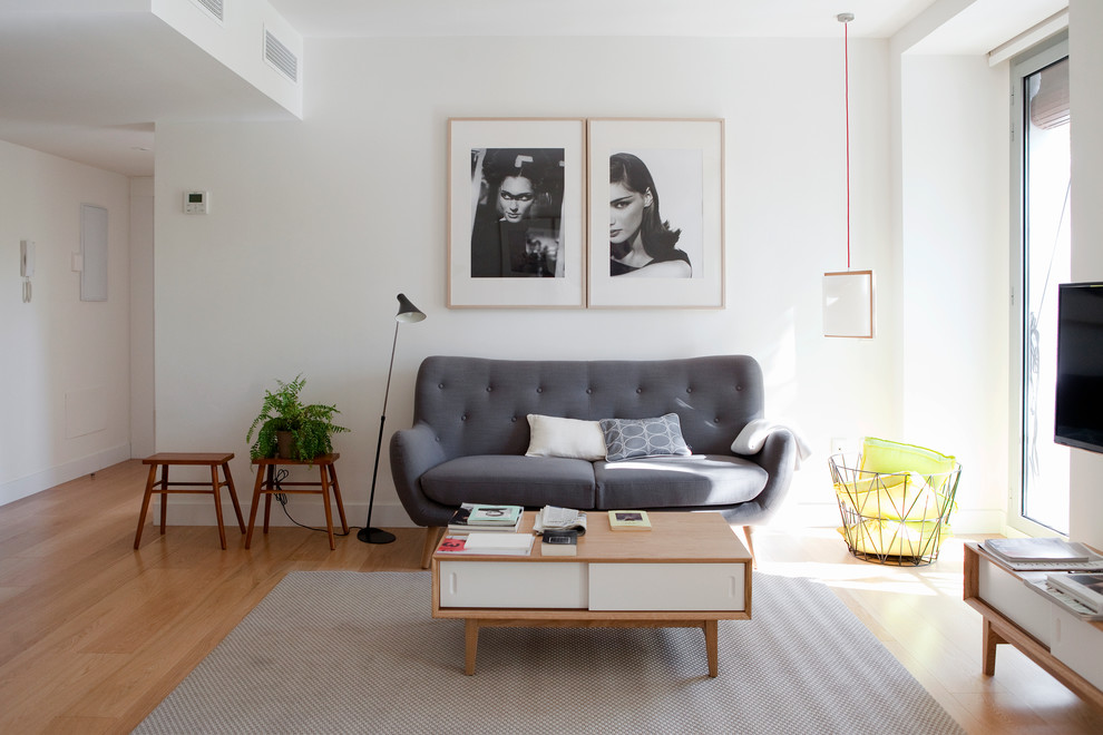 Foto på ett mellanstort funkis separat vardagsrum, med ett finrum, vita väggar, ljust trägolv och en fristående TV