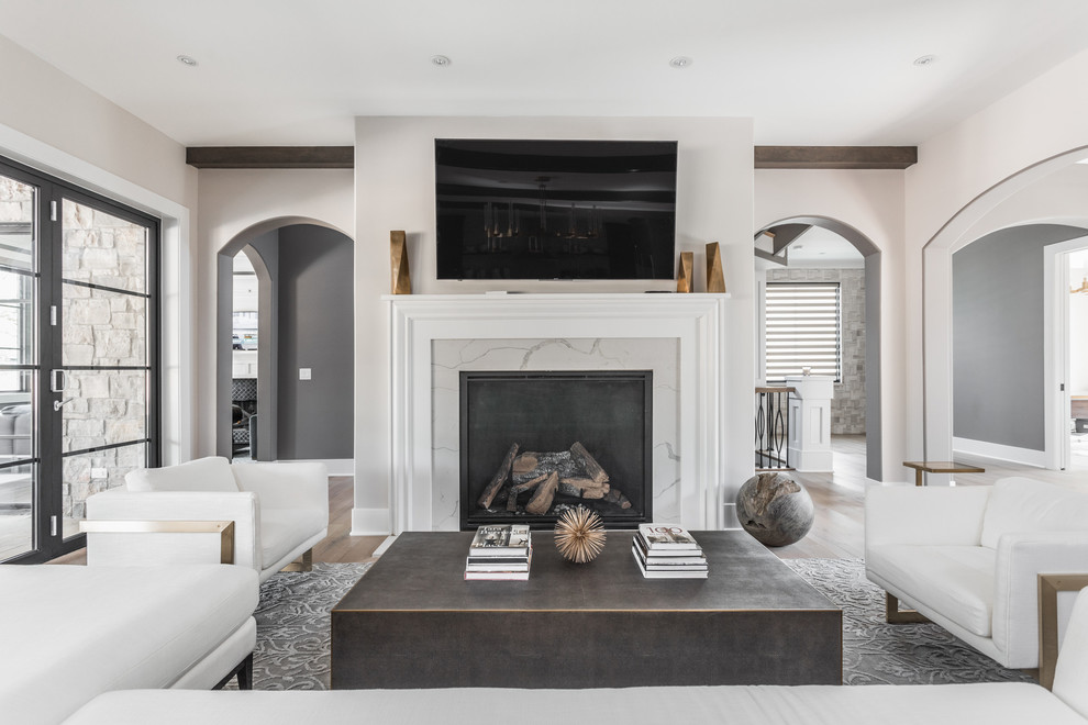 Large mediterranean open plan living room in Indianapolis with grey walls, medium hardwood flooring, a standard fireplace, a tiled fireplace surround and a wall mounted tv.