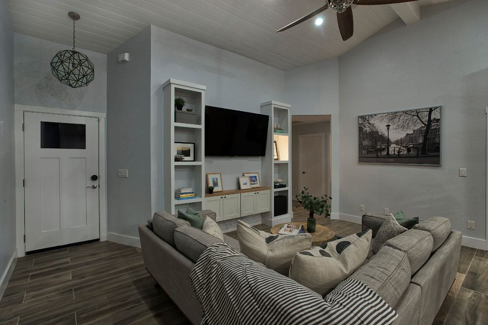 Foto de salón abierto minimalista de tamaño medio con paredes grises y televisor colgado en la pared