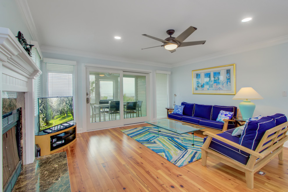Mittelgroßes, Offenes Klassisches Wohnzimmer mit blauer Wandfarbe, hellem Holzboden, Kamin, gefliester Kaminumrandung, freistehendem TV und gelbem Boden in Charleston