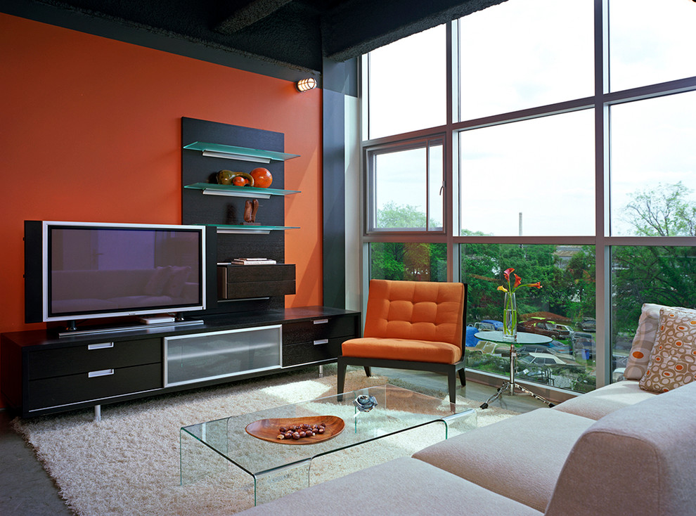 На фото: открытая гостиная комната в стиле модернизм с оранжевыми стенами, бетонным полом и отдельно стоящим телевизором с