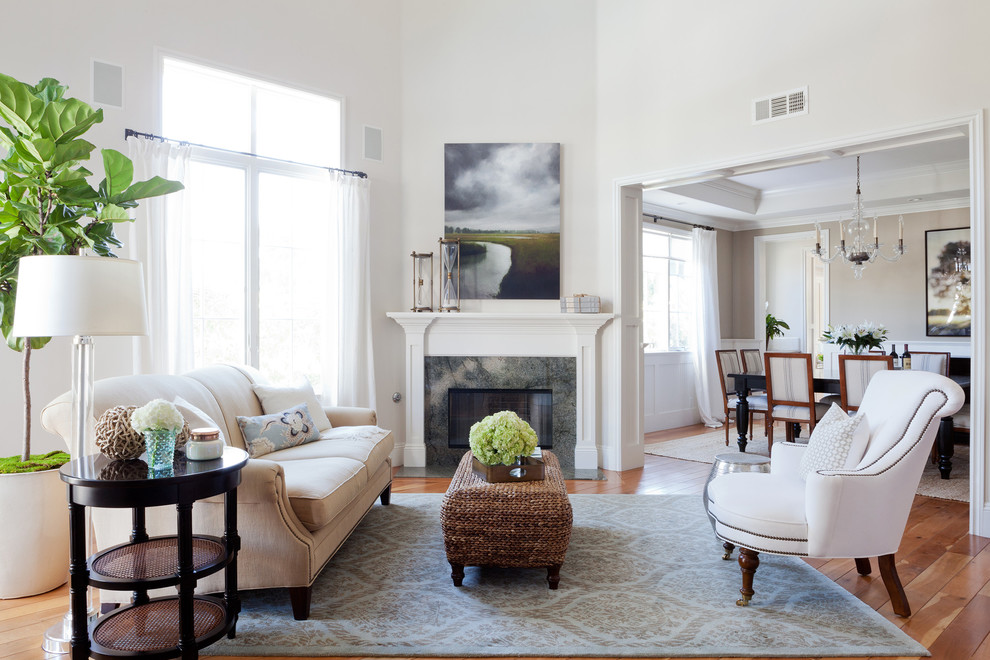 Modelo de salón para visitas abierto clásico sin televisor con paredes blancas, suelo de madera en tonos medios, chimenea de esquina y alfombra