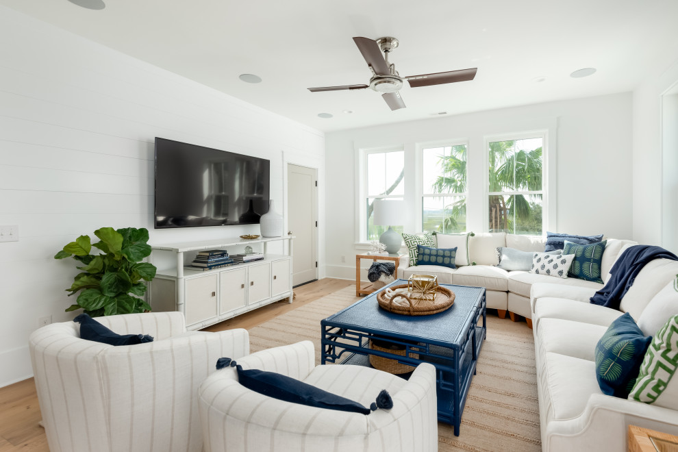 Стильный дизайн: открытая гостиная комната среднего размера в морском стиле с белыми стенами, светлым паркетным полом и телевизором на стене - последний тренд