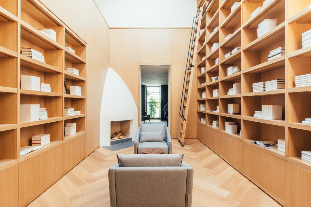 Inspiration för ett funkis separat vardagsrum, med ett bibliotek, beige väggar, ljust trägolv, en öppen hörnspis, en spiselkrans i tegelsten och beiget golv
